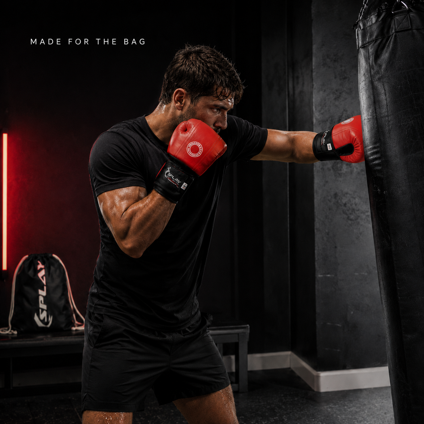 Boxer training on a punch bag wearing red and black SPLAY leather bag mitts